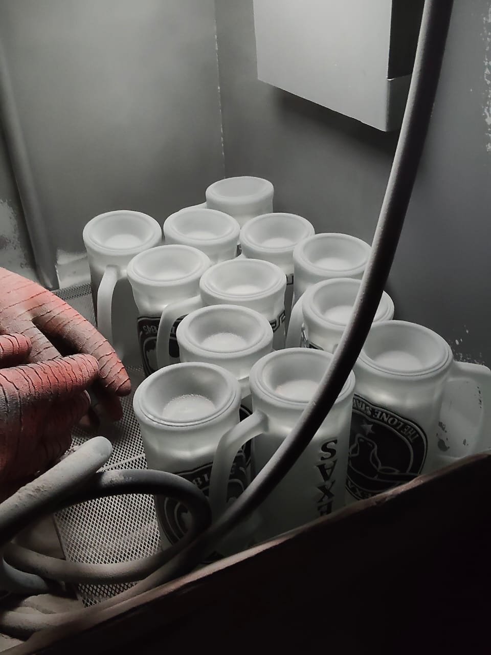 Small batch glassware undergoing traditional sandblasting engraving process